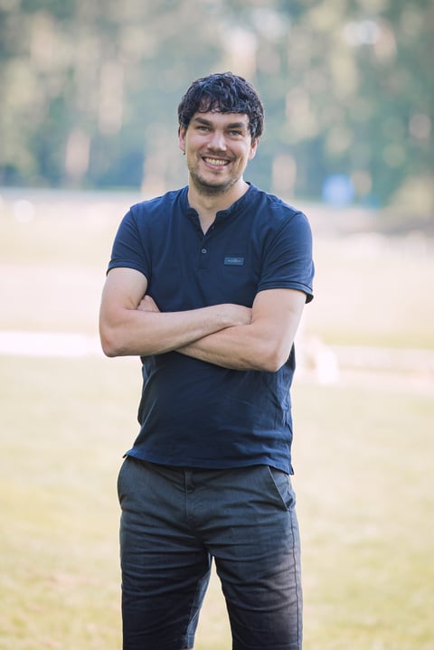 Marcel Landeweerd, oprichter van TextChecker.nl, in donkerblauw poloshirt en spijkerbroek, glimlacht naar de camera met wazige buitenachtergrond